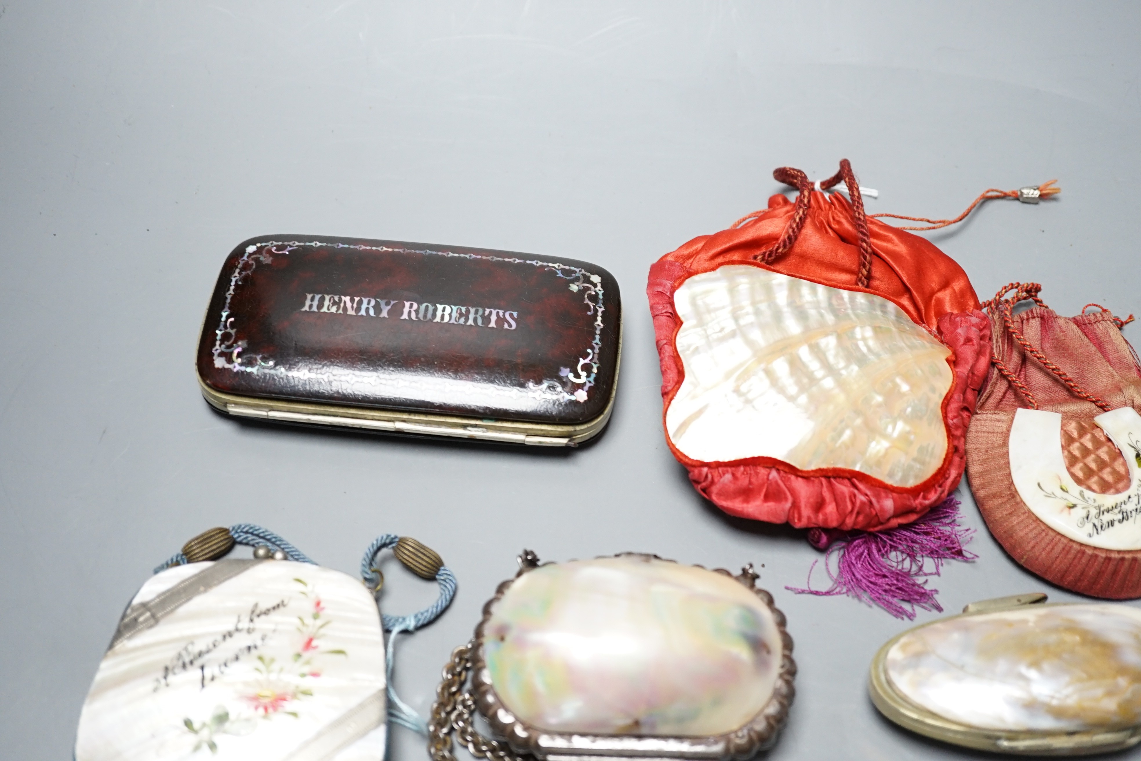 A collection of six mother of pearl souvenir purses, possibly from a grand tour and a papier-mâché mache card case and glasses case, card case 14 cms wide